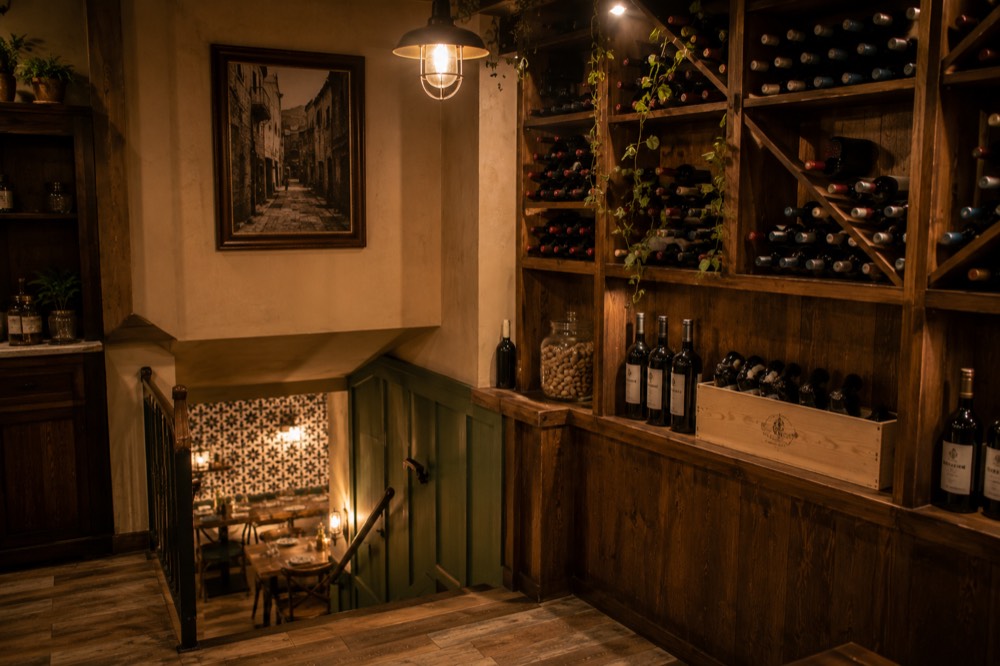 Избата — сводест таван, рафтове с вино и маси за малки компании. / The cellar — a vaulted ceiling, wine shelves and tables for small parties.